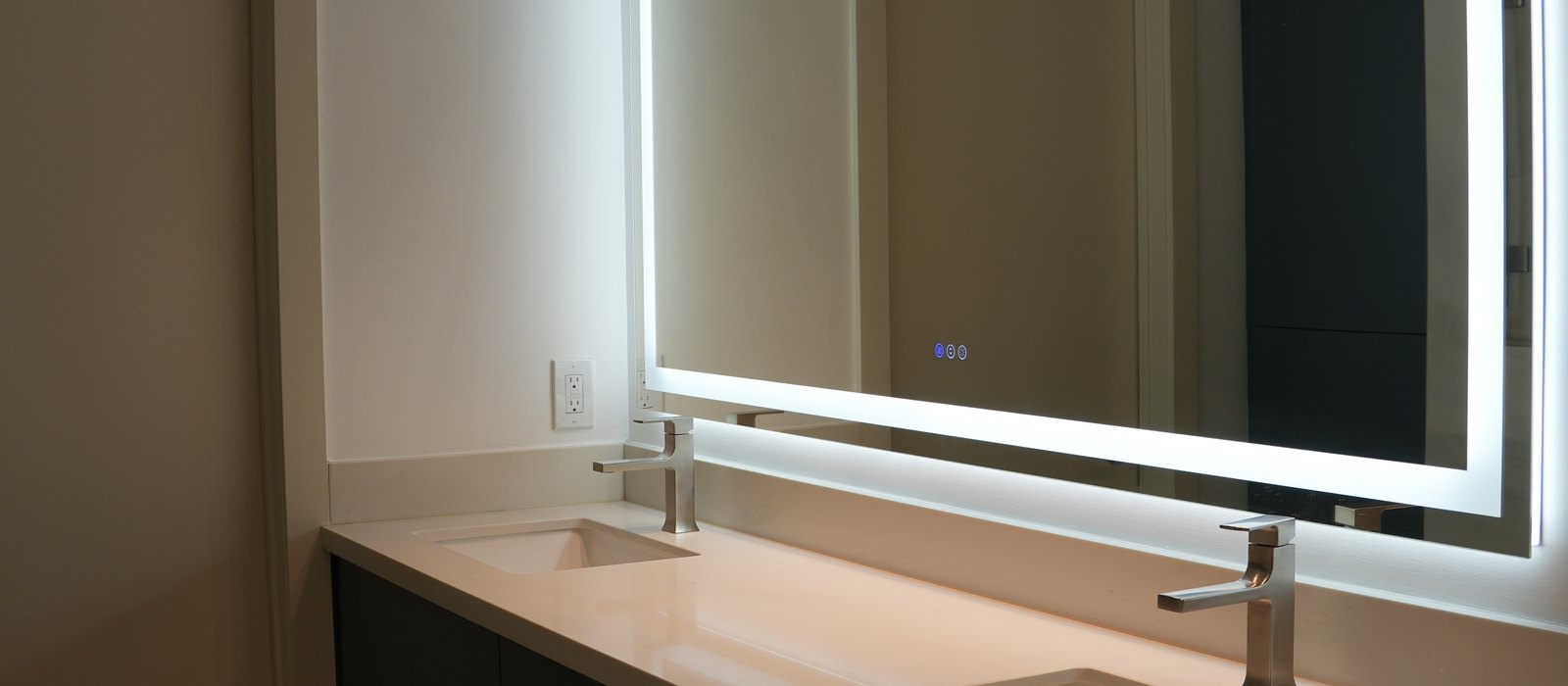 Bathroom remodel by Haven Renovations — backlit mirror over a quartz double vanity