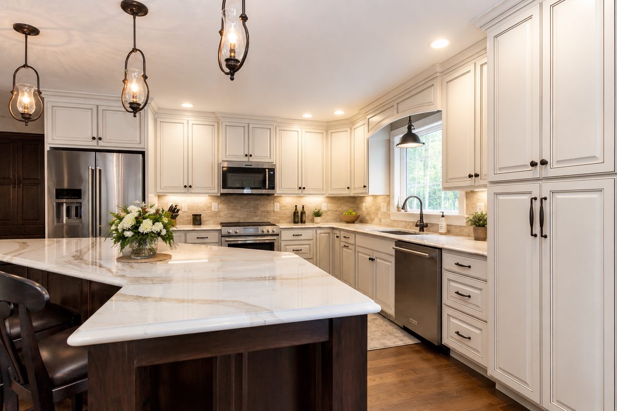 Cream raised-panel cabinetry with a dark stained island and white marble counters