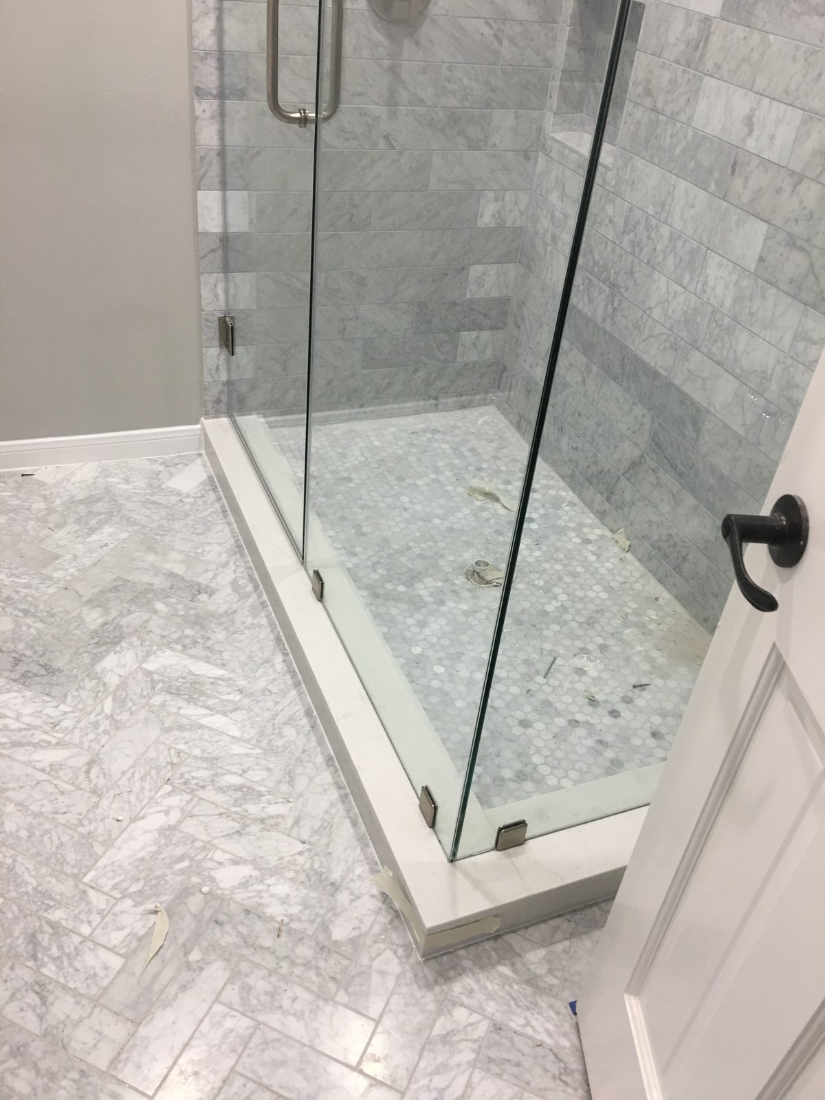 Glass shower stall with marble tile surround