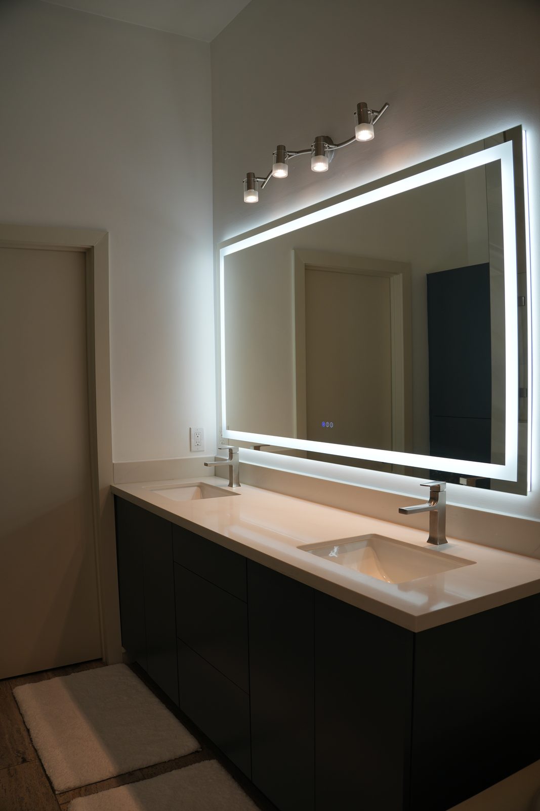 Backlit LED mirror above a dark floating vanity